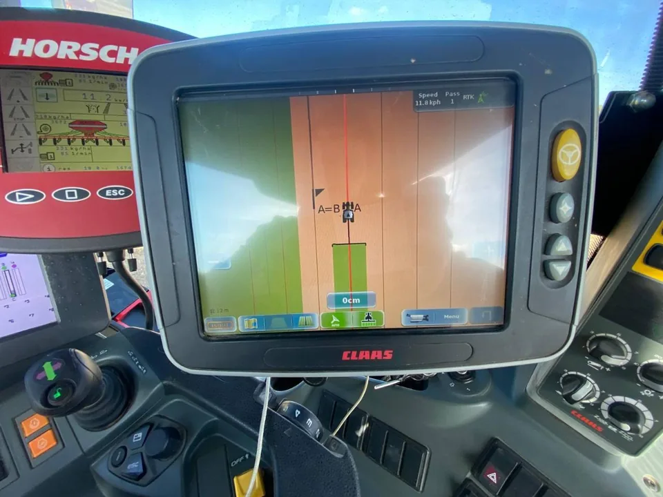 CLAAS guidance terminal in a tractor cab showing field guidance lines and RTK status